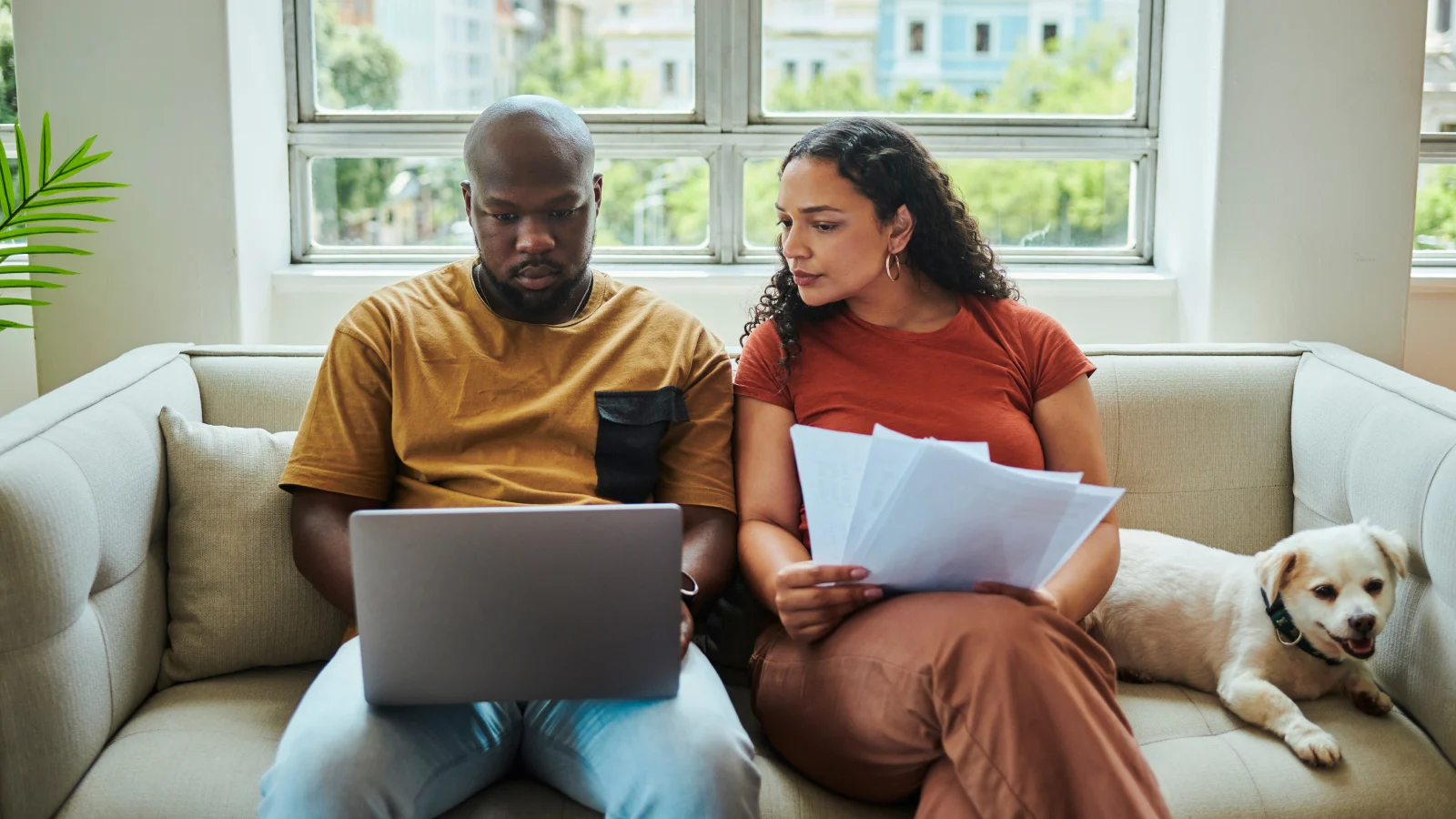 Couple completing tasks on a laptop at home.