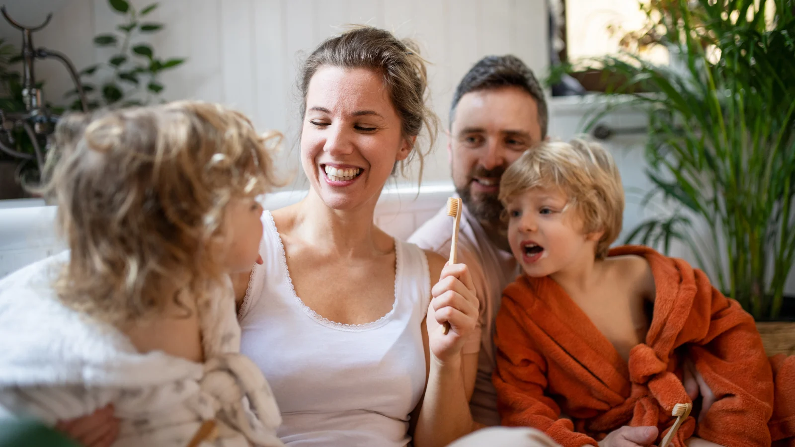 An Ounce of Prevention: The link between preventive dental care, better oral health, and overall wellness - Parents smiling with children on the couch 