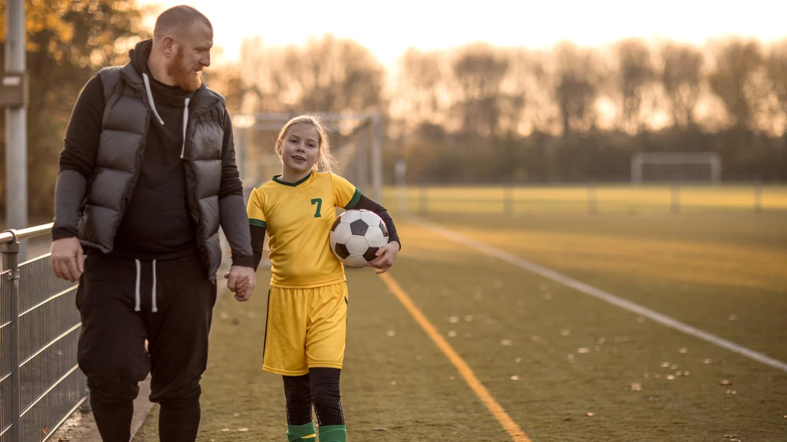 Father holding his daughter's hand after her soccer game