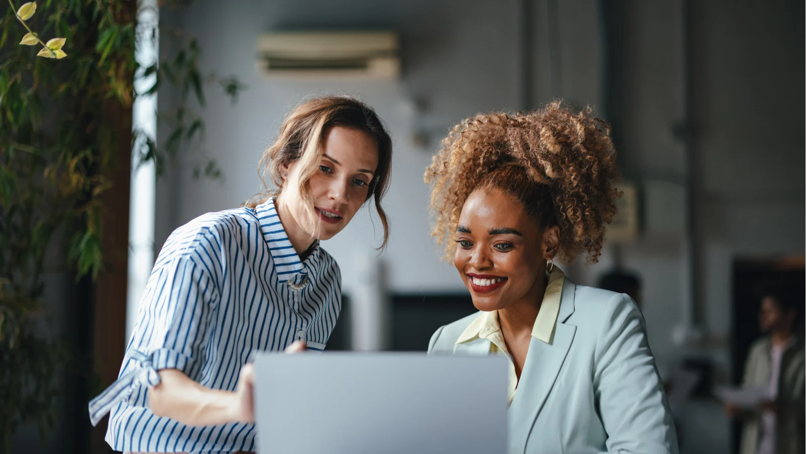 Female small business owner working with her female broker in front of a computer