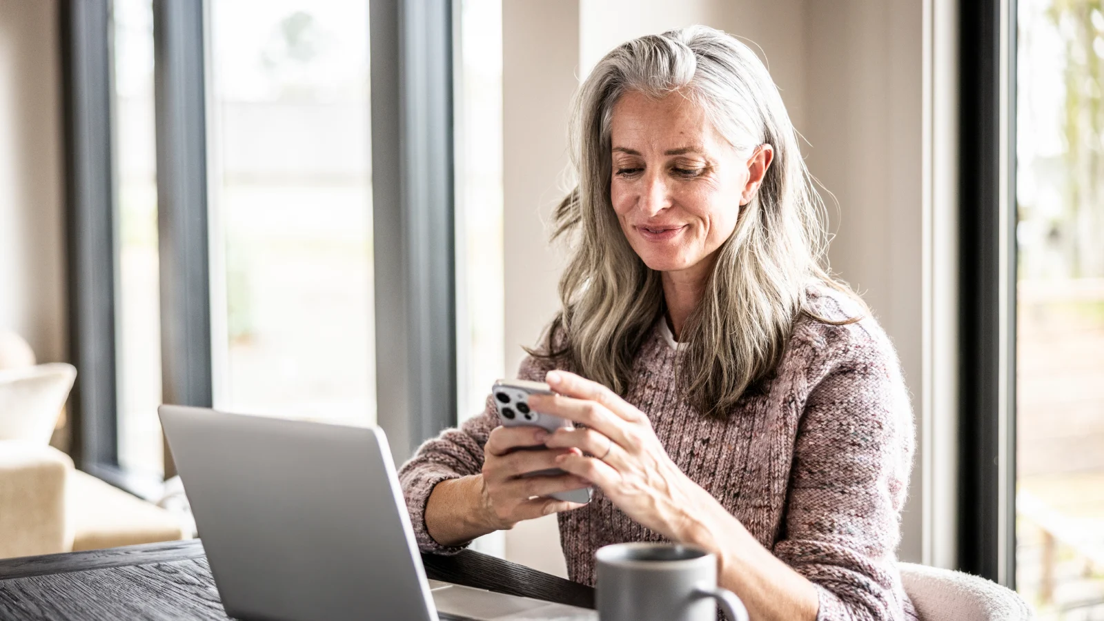 Senior woman using smartphone and laptop