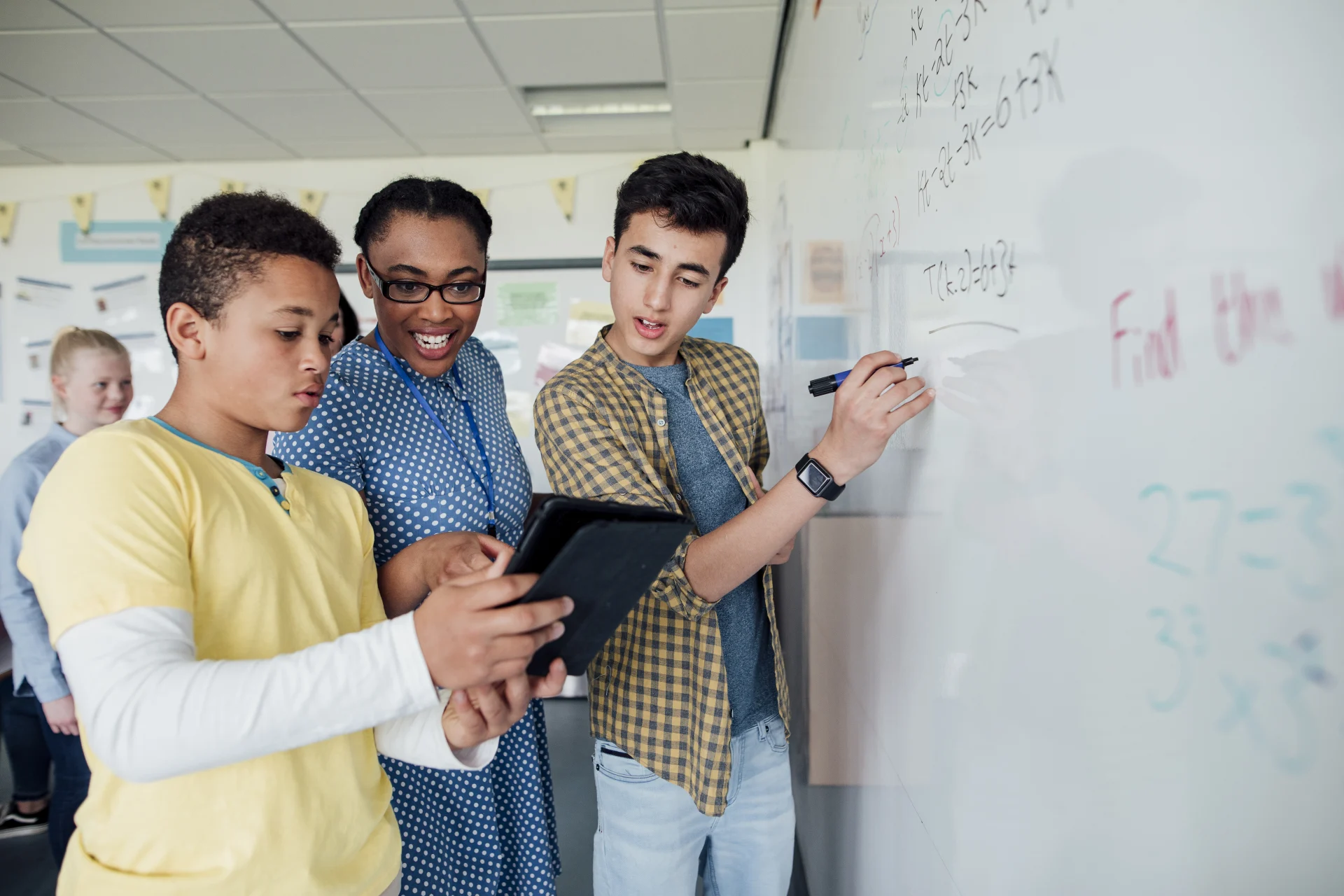 Scholarly Stress: High turnover, teacher burnout, and industry changes challenge the education sector - Two students with their teacher working on a problem at the white board. 