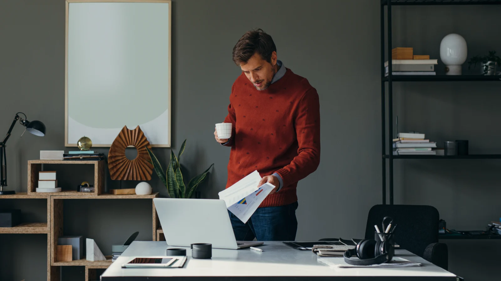 Businessman standing up and reading something on his computer.