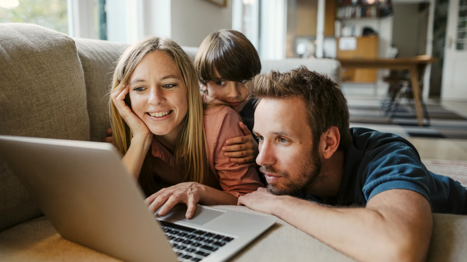 Access to a dedicated, clinically-licensed Family Navigator  - parents looking at laptop with kid on couch