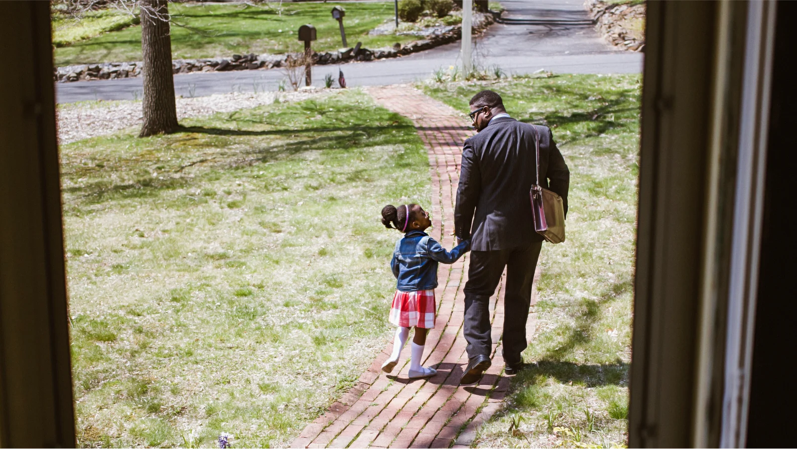 Businessman leaving for work from his house holding his daughter's hand