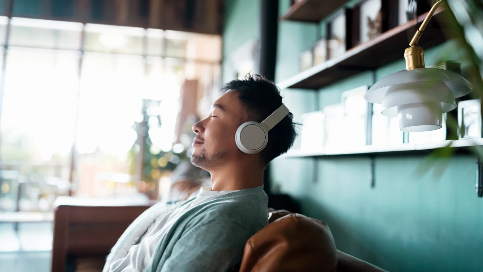 Man with his hands behind his head listening to music on his couch.
