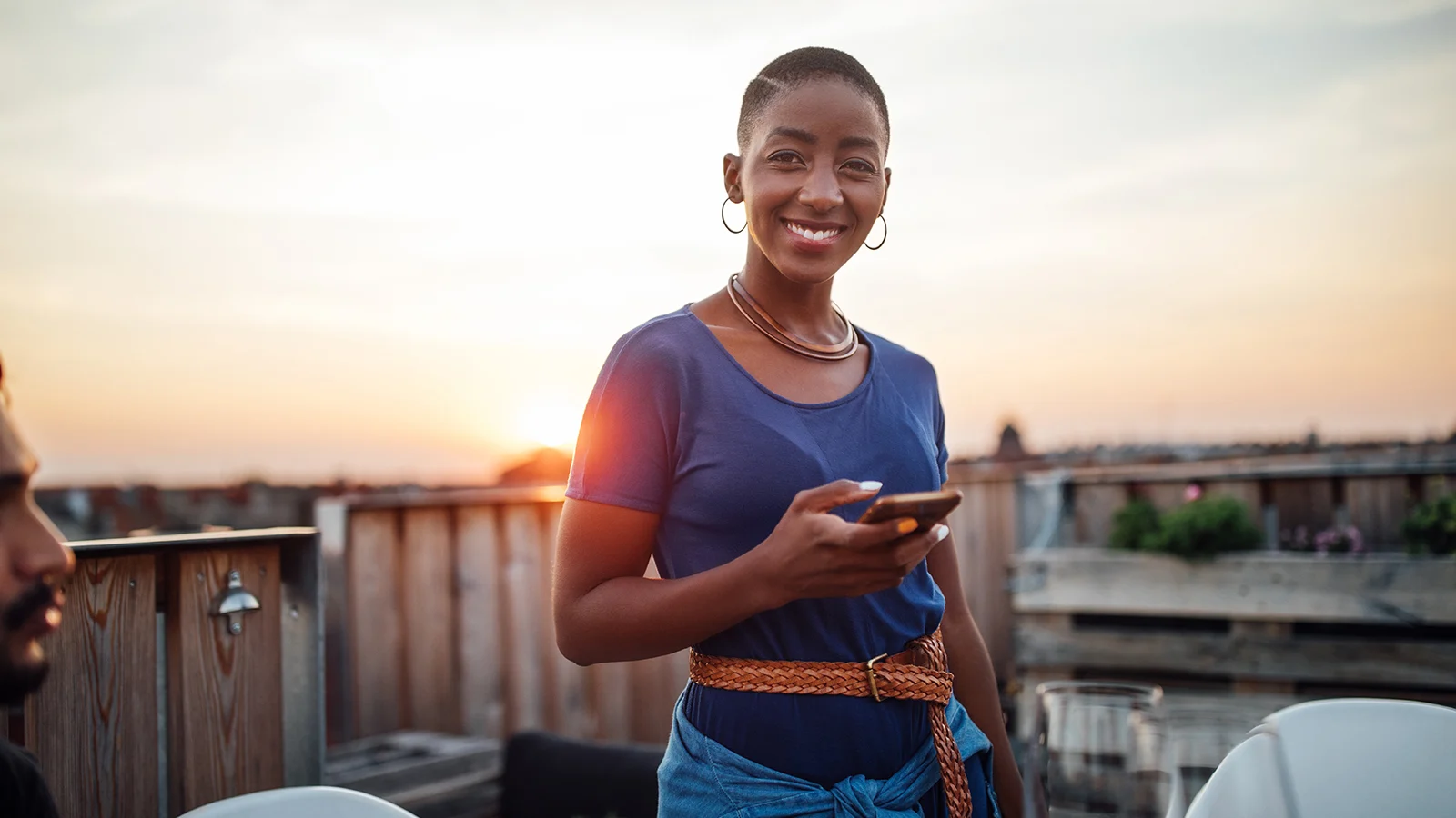 Putting policyholders first - Woman smiling in front of a sunset and holding her mobile phone