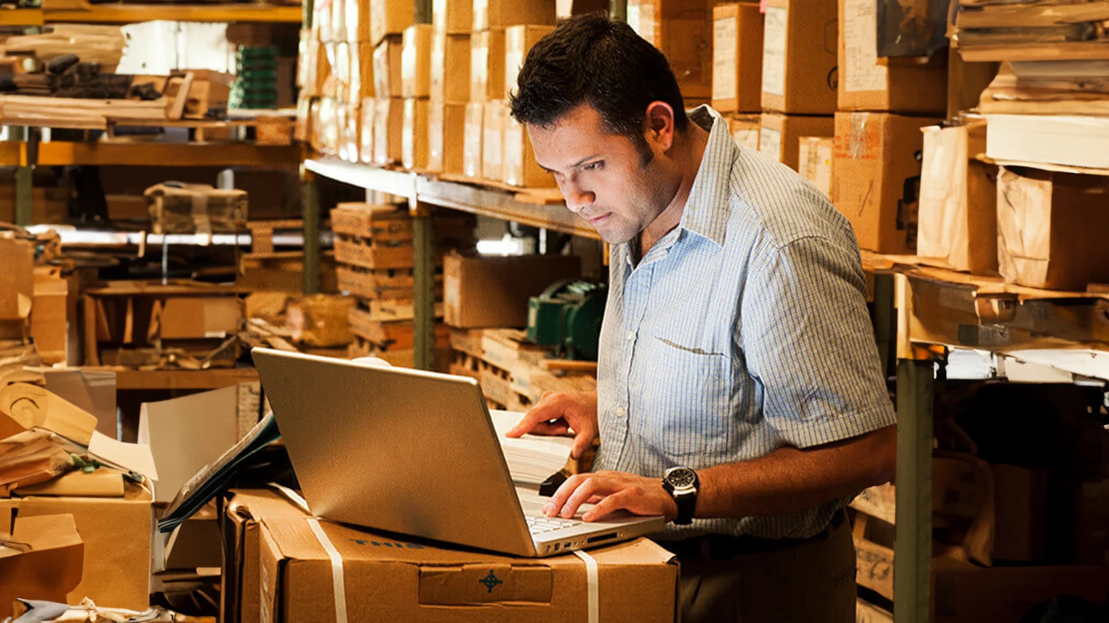 Hispanic manager working on his laptop in the warehouse