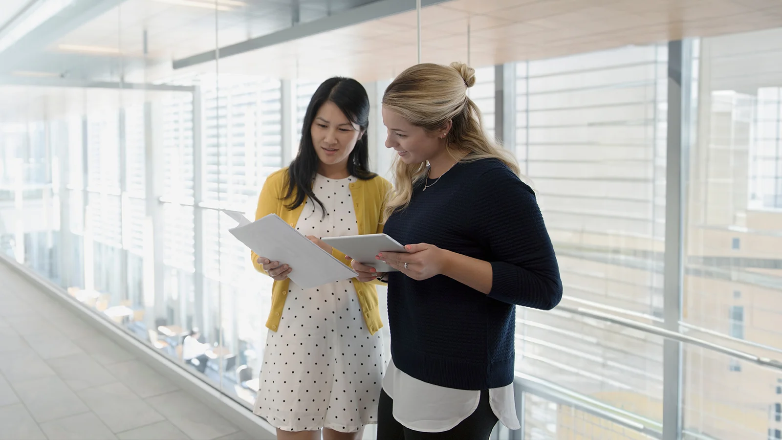 Two employees standing in the hallway looking over paperwork