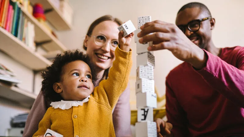 Term life insurance - Mother, father and toddler happily playing with building blocks