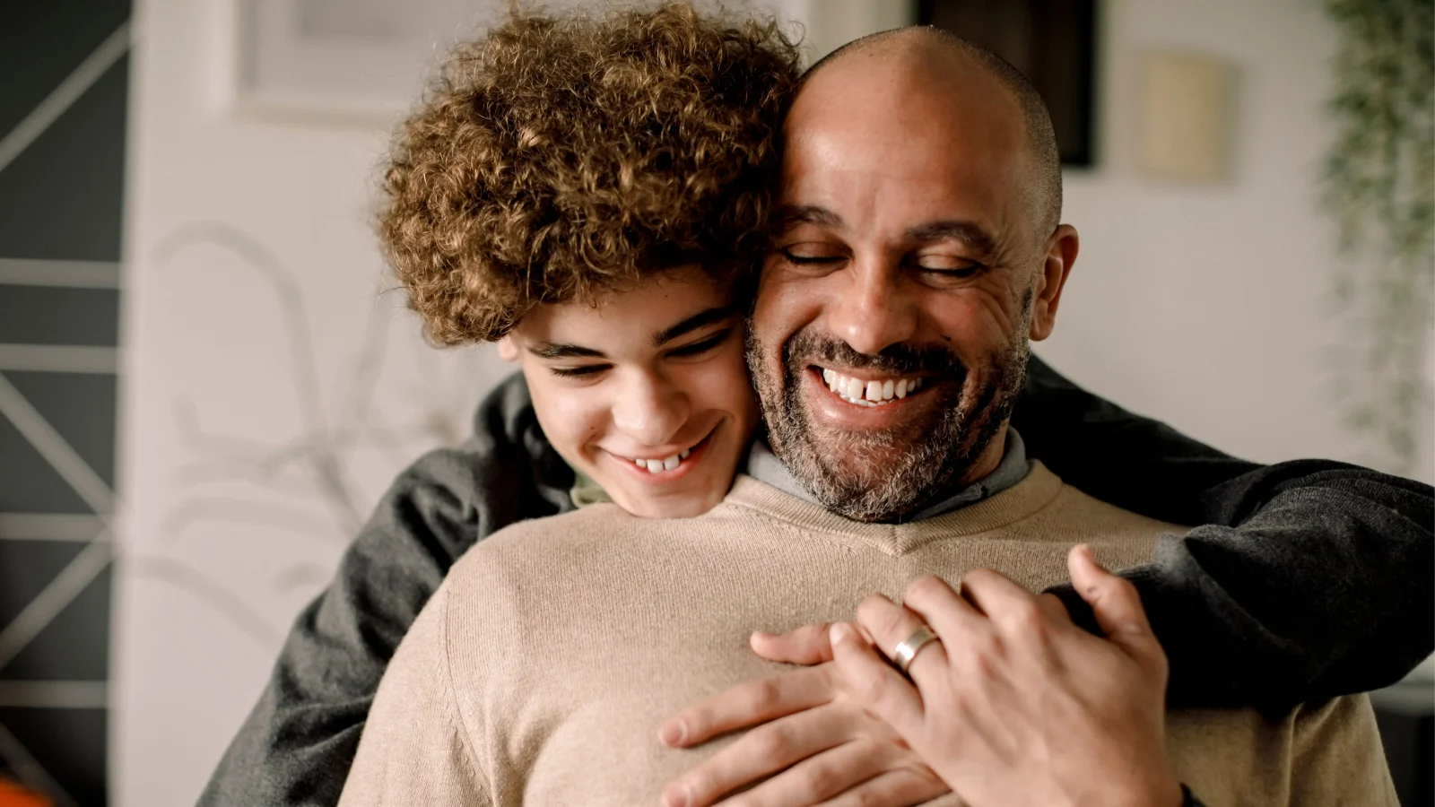 Teenage son hugging his father from behind.