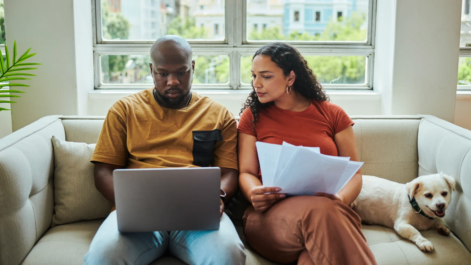Couple sitting on a couch and looking at a laptop together.