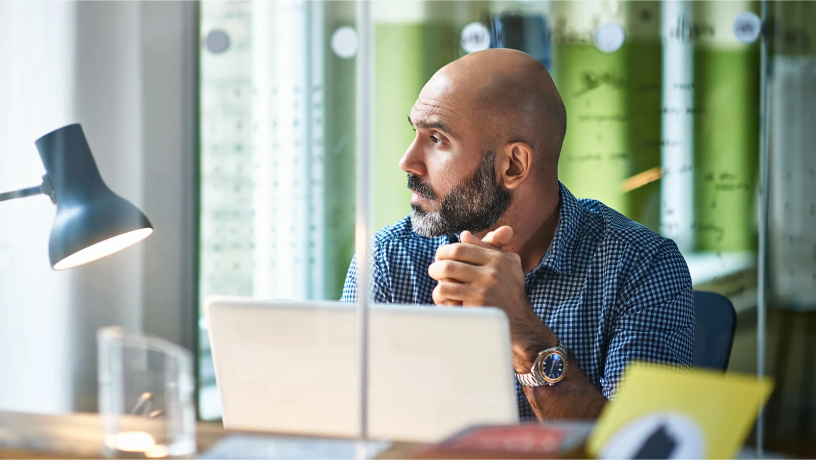 Mental wellness + disability - man sitting at office desk looking out window