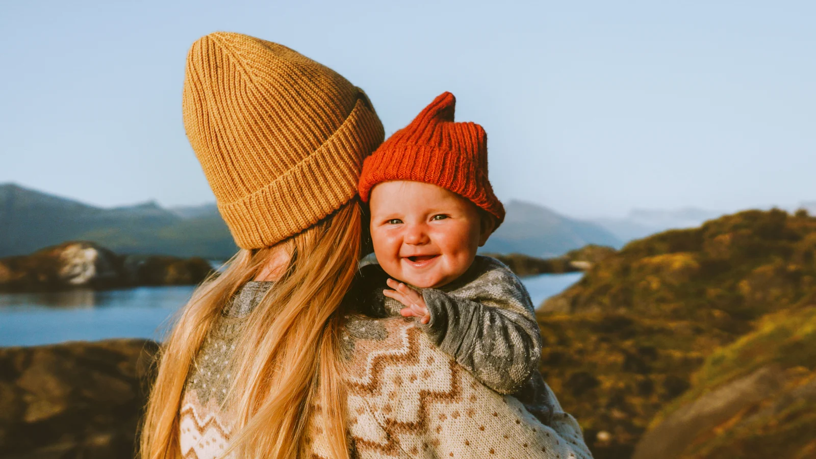 Mother holding smiling baby outside.