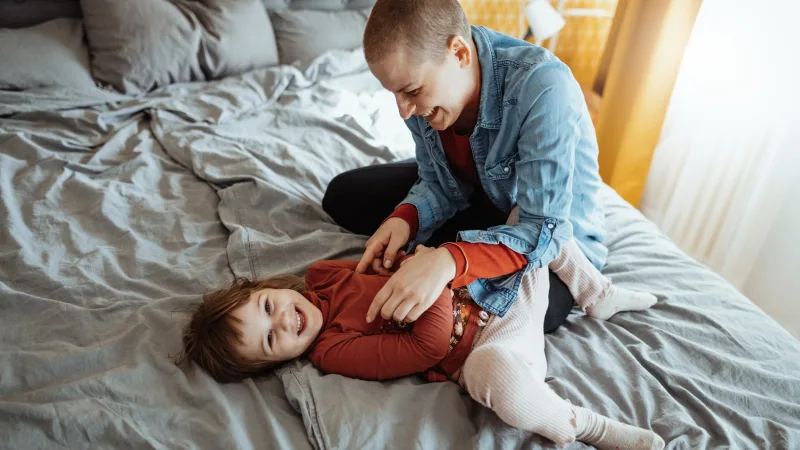 Cancer insurance - Cancer patient mother playing with young daughter and laughing