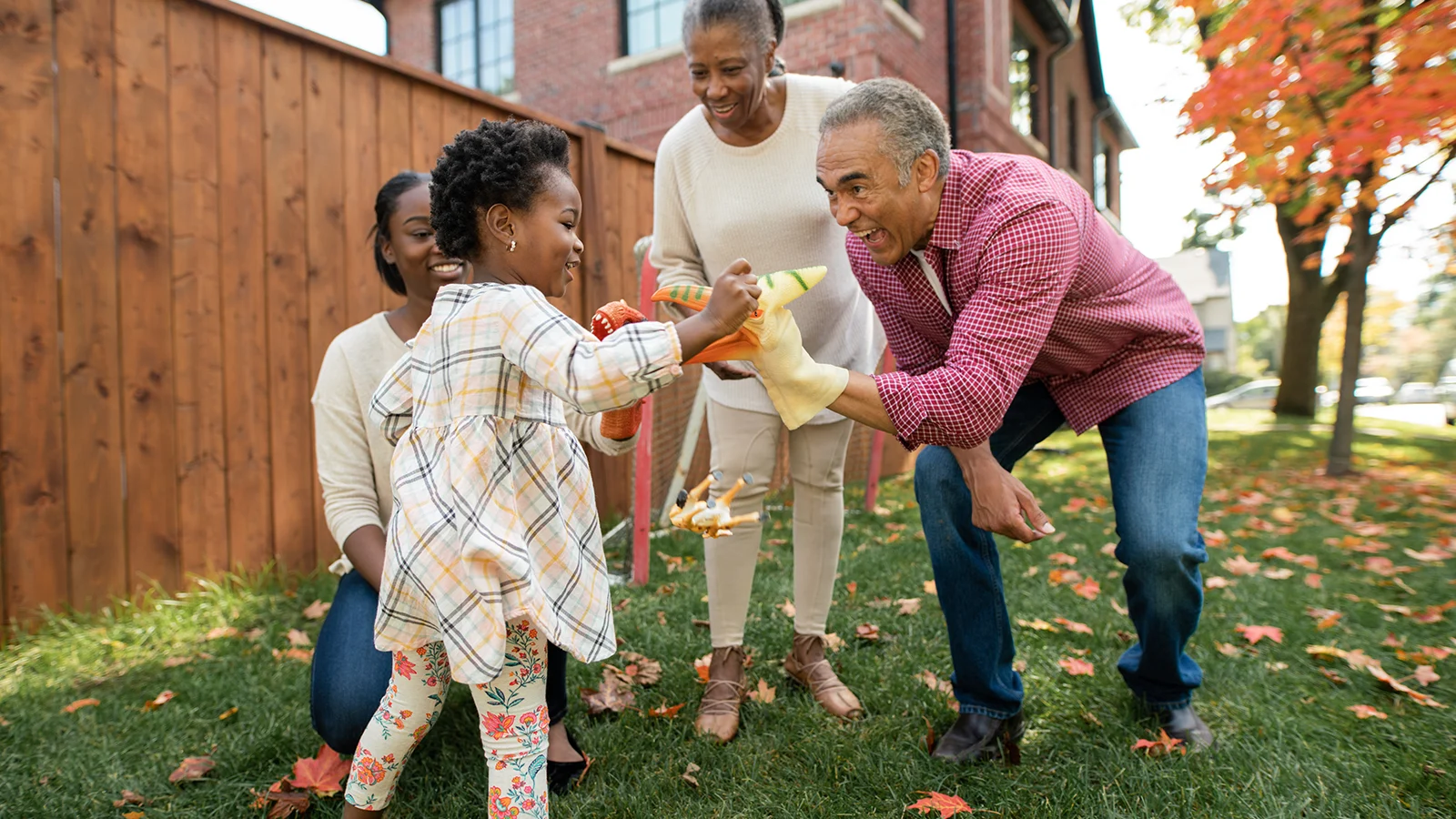 Grandfather with a puppet on his hand playing with his granddaughter