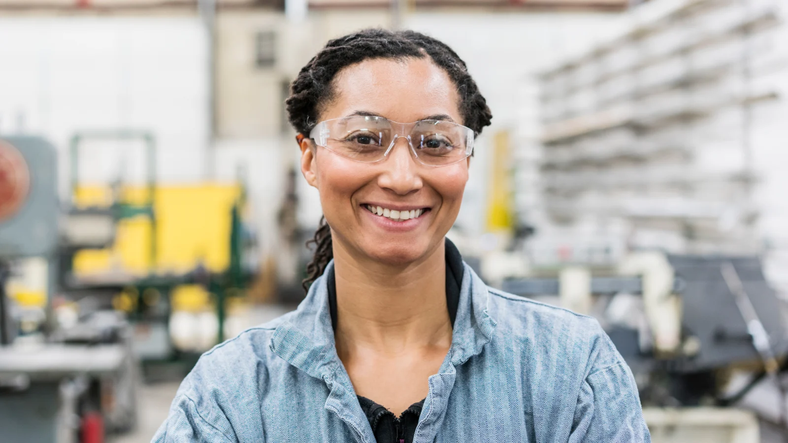 Female manufacturing worker smiling with safety glasses on.