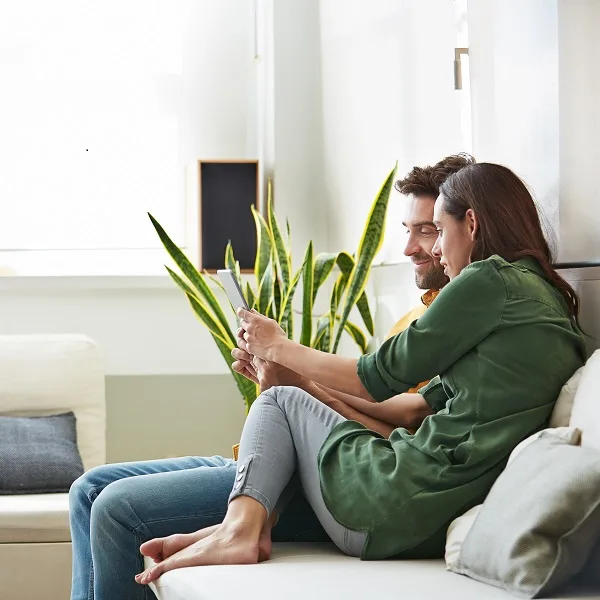 Couple on a couch looking at a tablet.