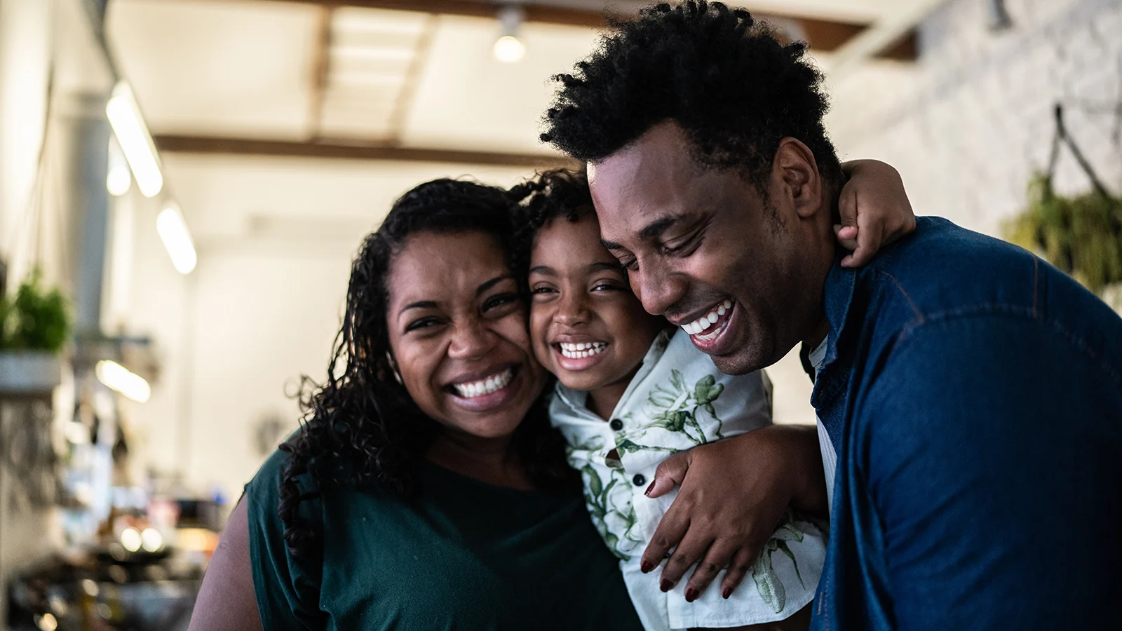 Three people embracing and smiling together at home, representing family caregiving and leave benefits covered by New Jersey's expanded job-protected leave protections.