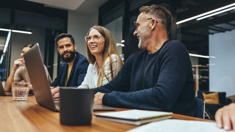 For employers: How supplemental health insurance supports employee well-being - Coworkers talking in meeting