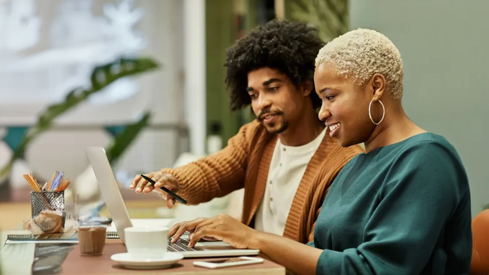 8 ways to improve your well-being, starting at work - Two coworkers look at a laptop, smiling.