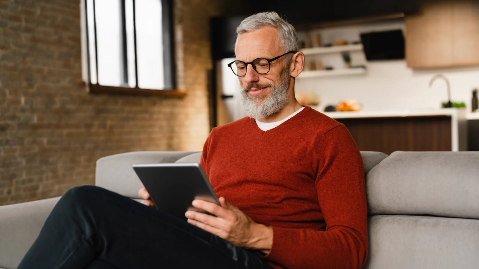 Man sitting on a couch looking at this tablet.