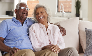 senior couple sitting on a couch laughing