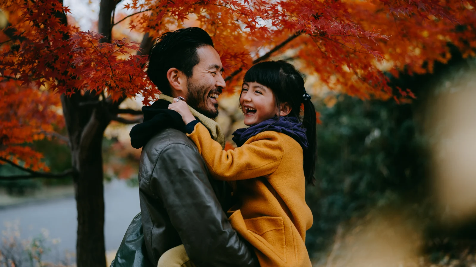 Supports well-being for the whole family - Father smiling and holding his daughters in his arms