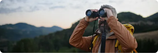 Financial and investment highlights - A man on a mountain looks into the distance with binoculars
