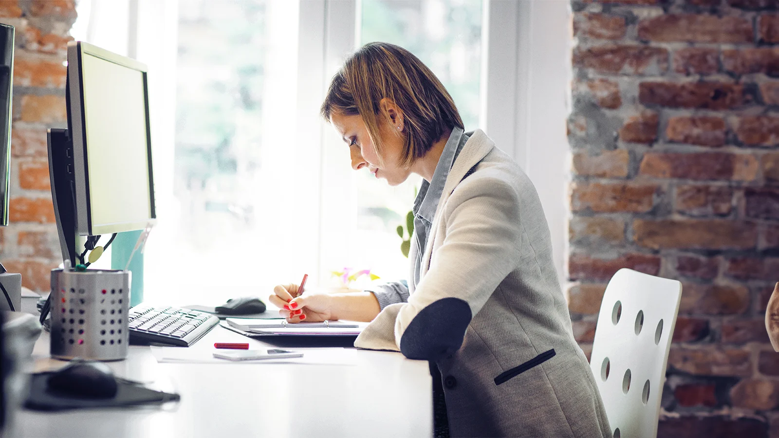 Woman writing in her notebook at her desk at work