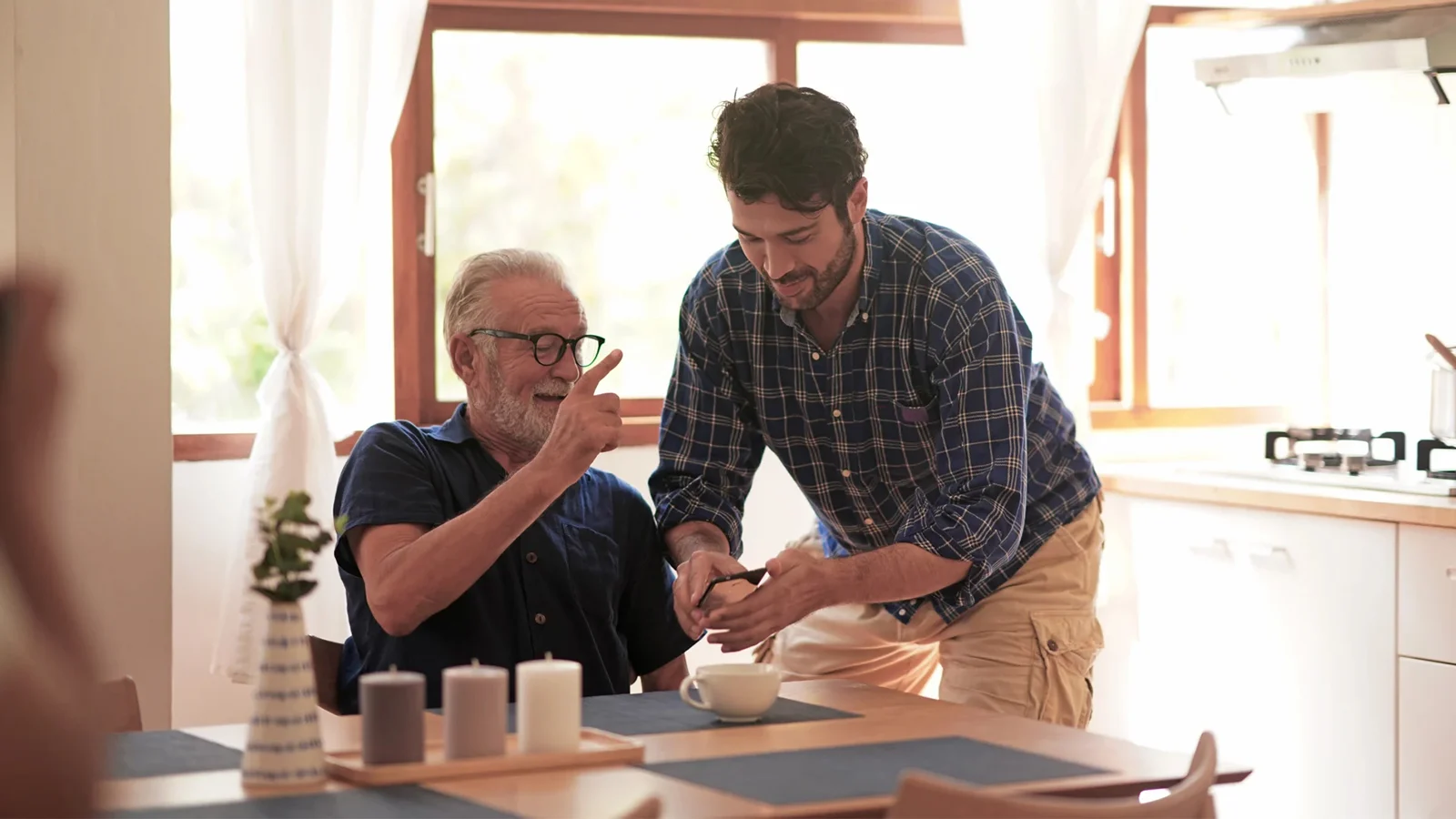 Adult son helping his father at a dining table.