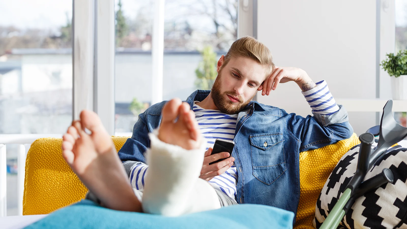 Disability insurance: definitions and terms you should know - Man with a cast on his broken foot looking at his phone