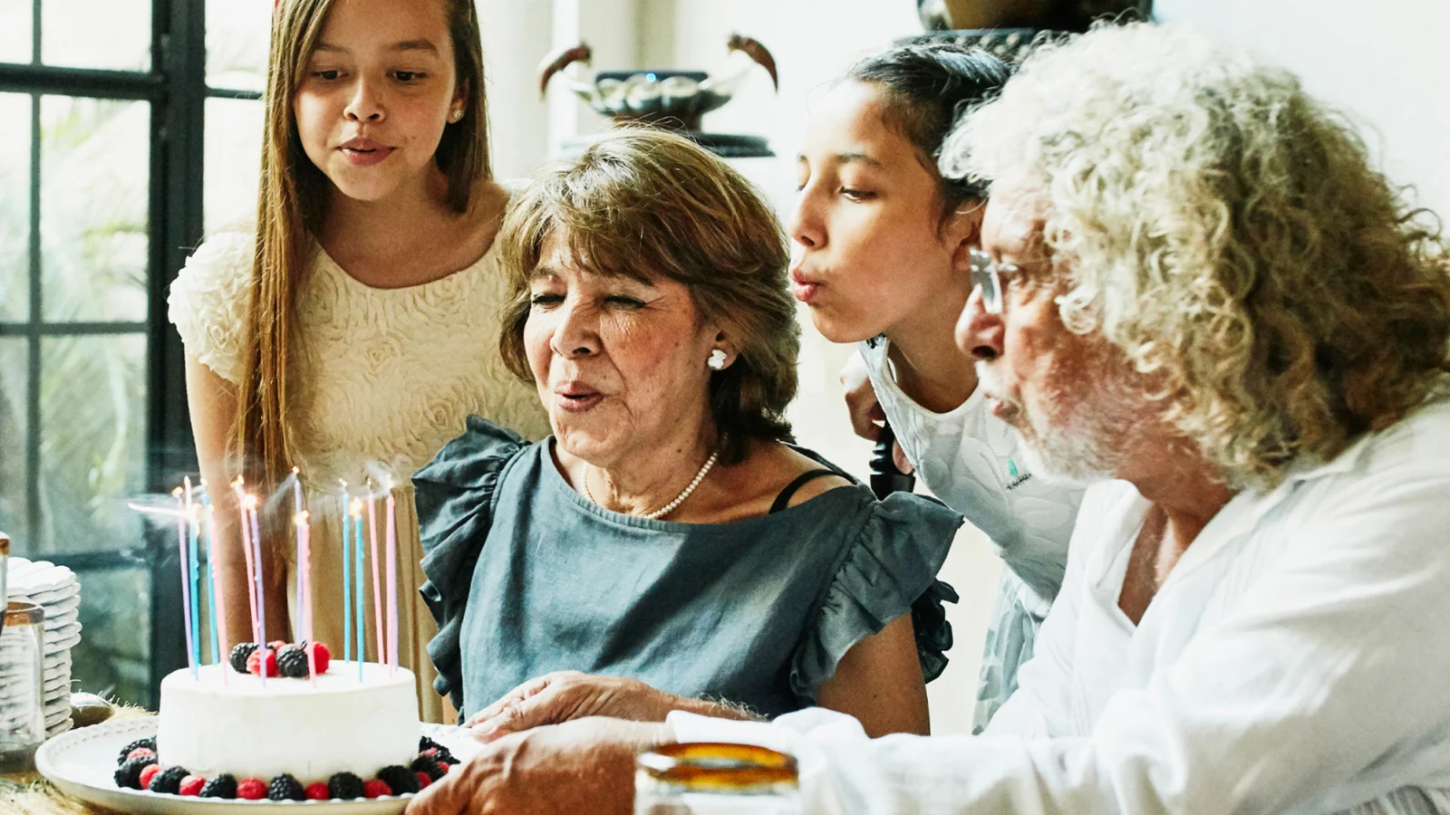 Grandmother blowing out birthday candles with her family