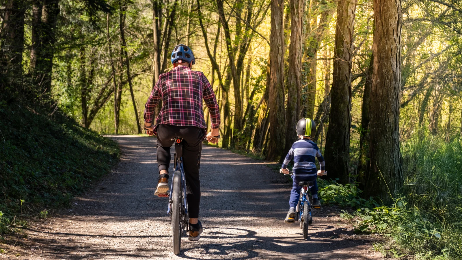 Father and son riding bikes outside.
