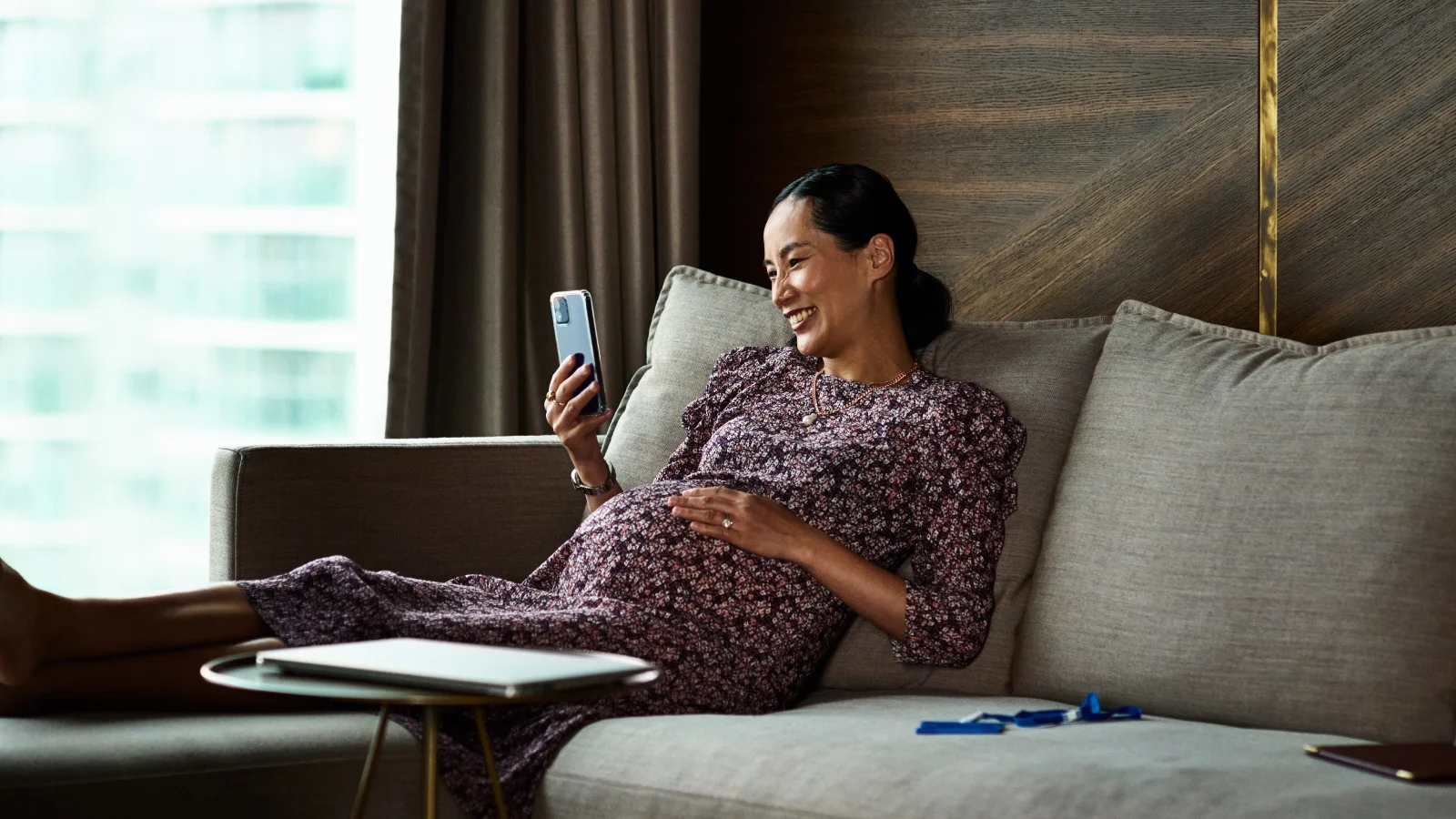 Pregnant woman sitting on a couch and looking at her phone. Pregnant woman sitting on a couch and looking at her phone.