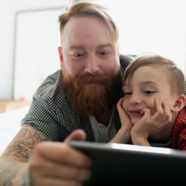 Man viewing tab with child.