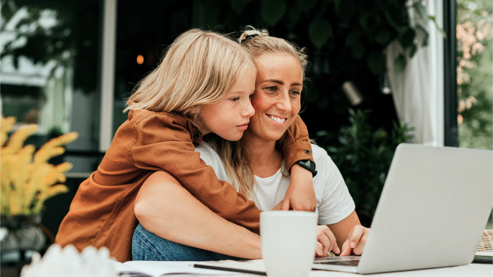 Benefits Enrollment Preparation - Smiling woman using laptop with son embracing her