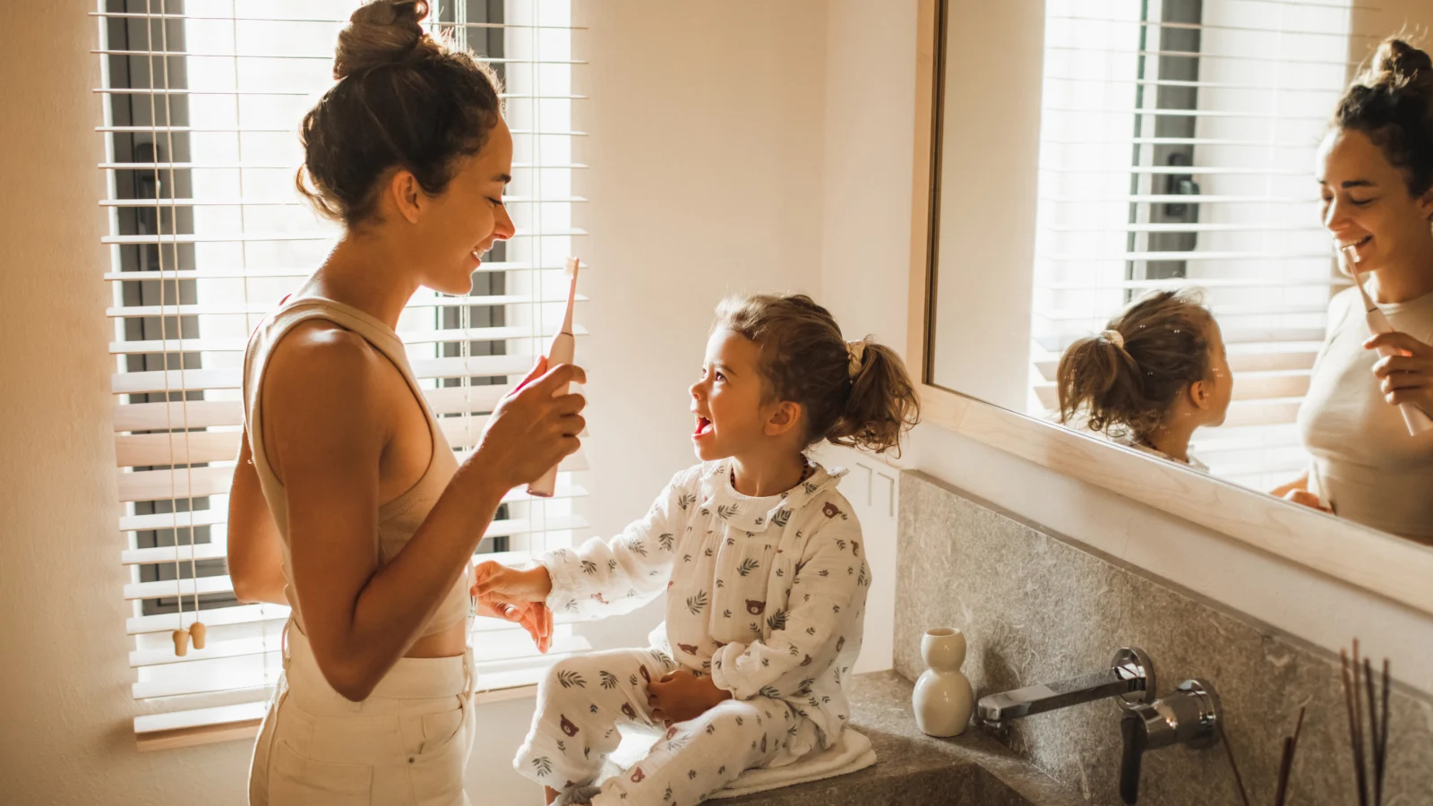Mother and daughter brushing their teeth together.