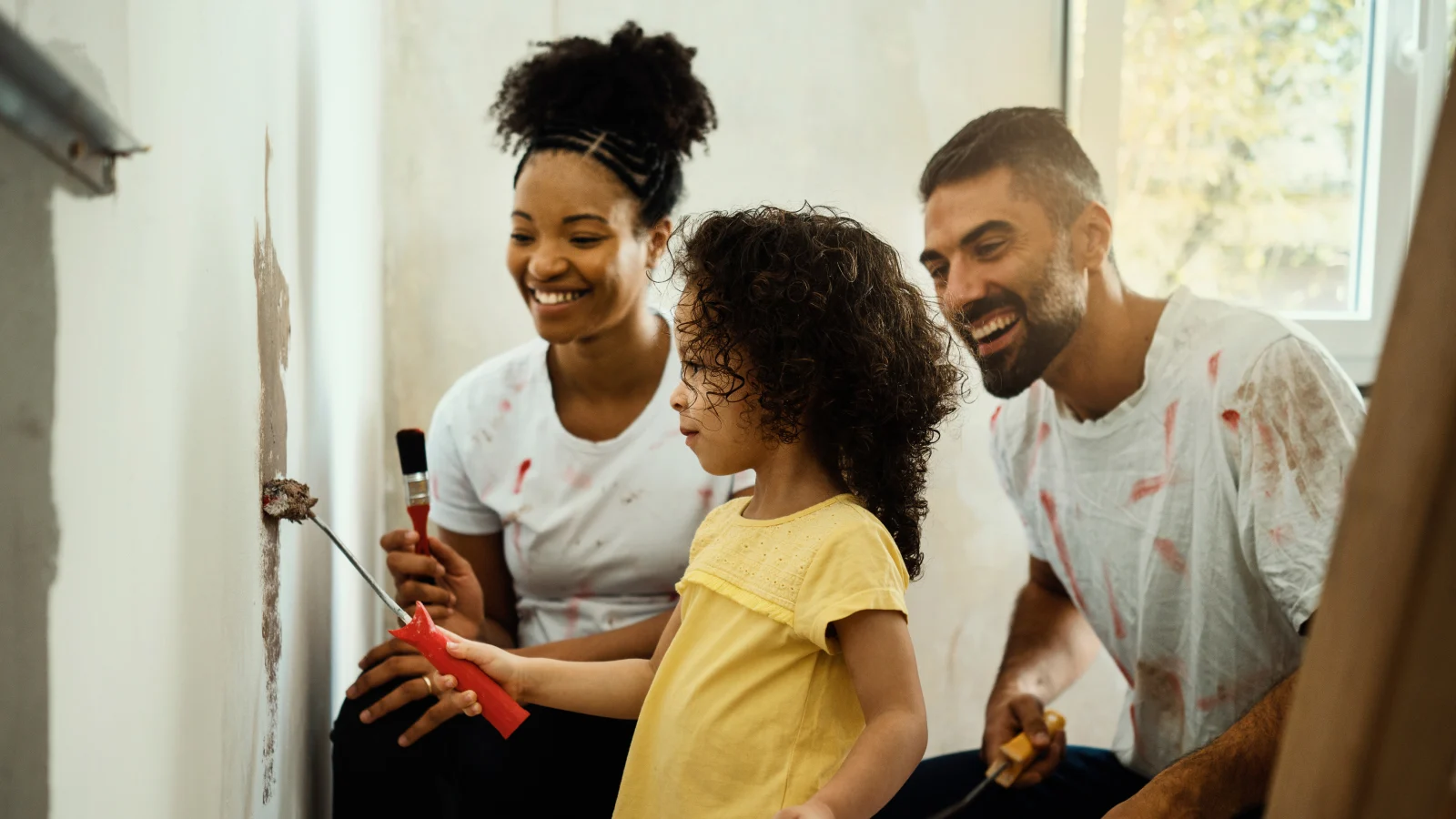 Happy family painting a wall together in their house