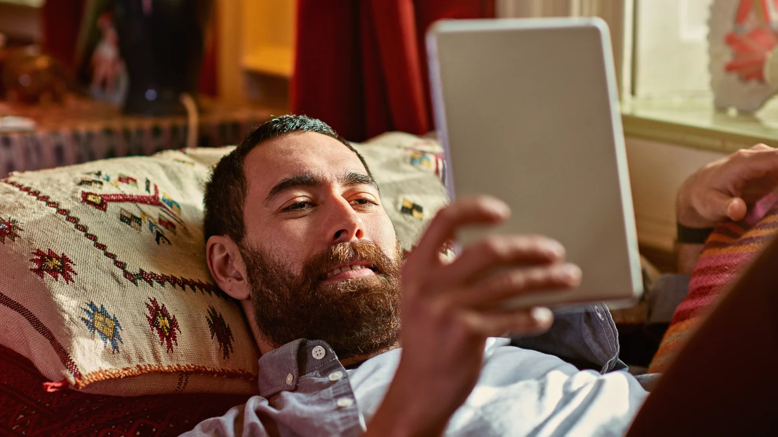 Intuitive mental wellness support - Man lying in bed reading his tablet