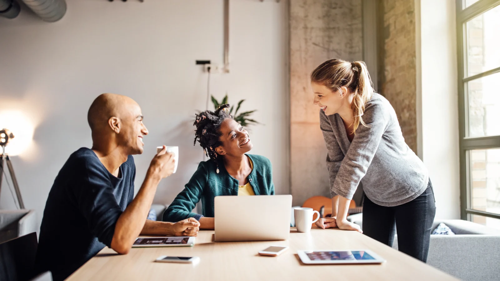 Colleagues talking while using laptop