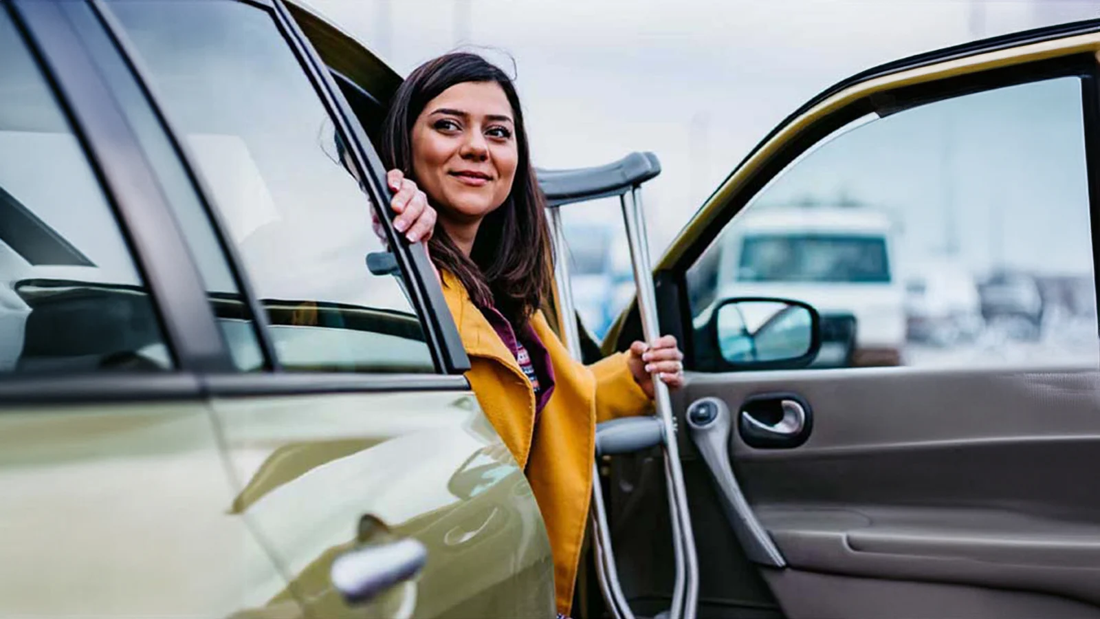 Woman getting out of her car carrying crutches