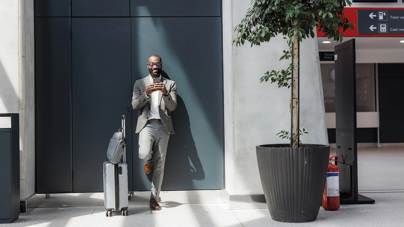 A professional standing by a wall and using phone
