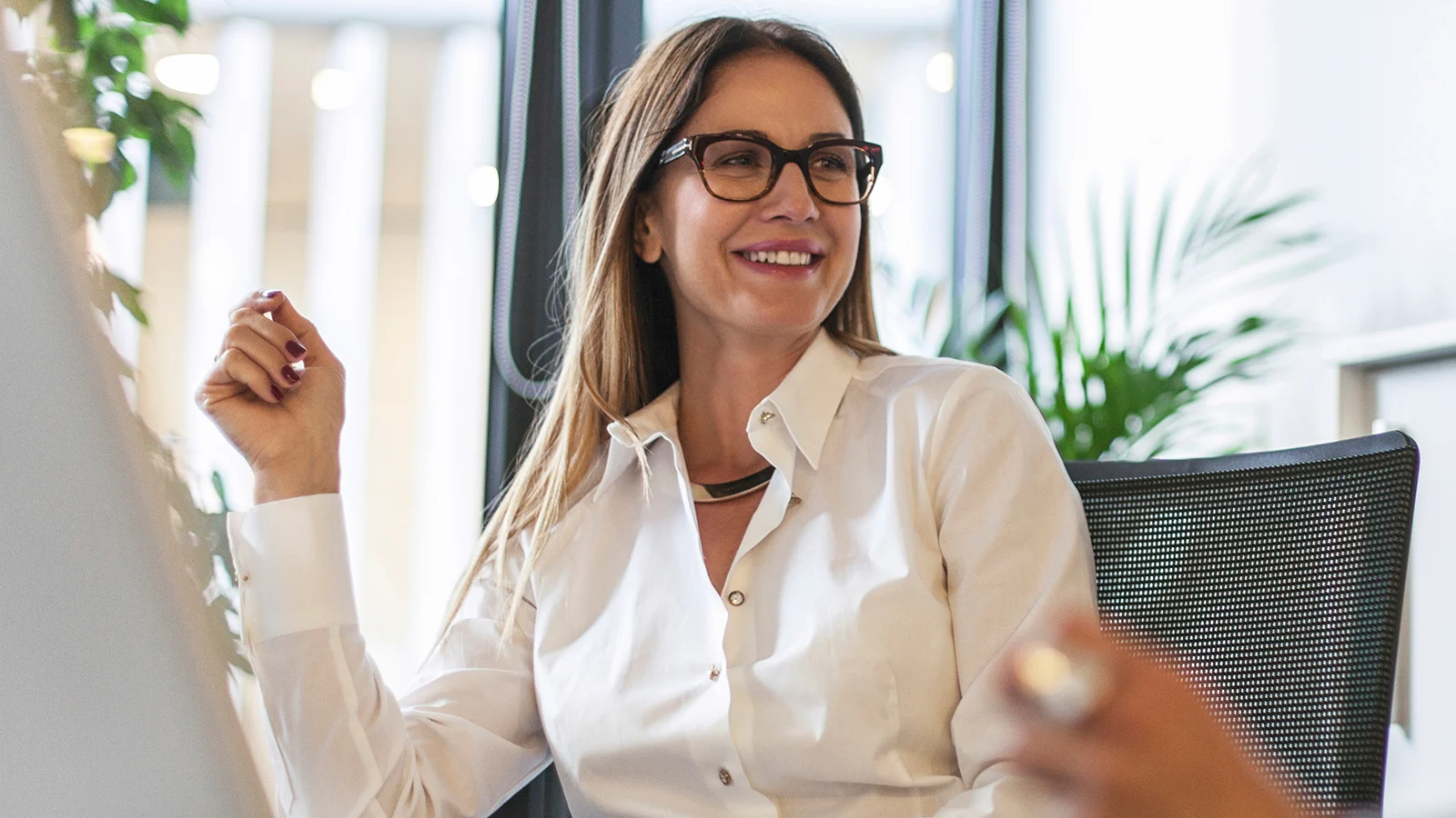 One woman wearing glasses smiling in office meeting