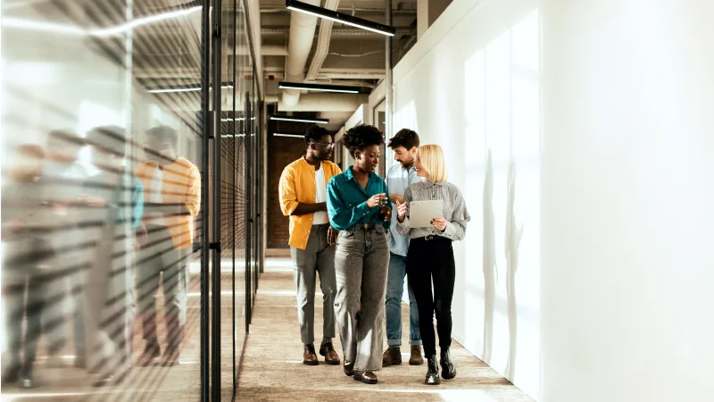 How to work with us - Team of employees walking and happily conversating in the office hallway