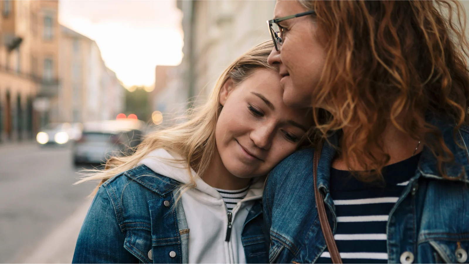 Teenage girl leaning on mothers shoulder