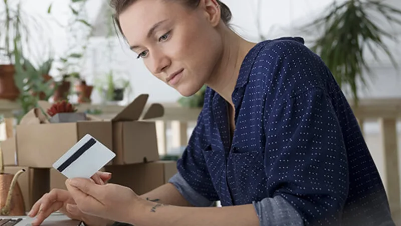 Managing higher out-of-pocket medical costs - Woman holding her credit card purchasing something on her laptop