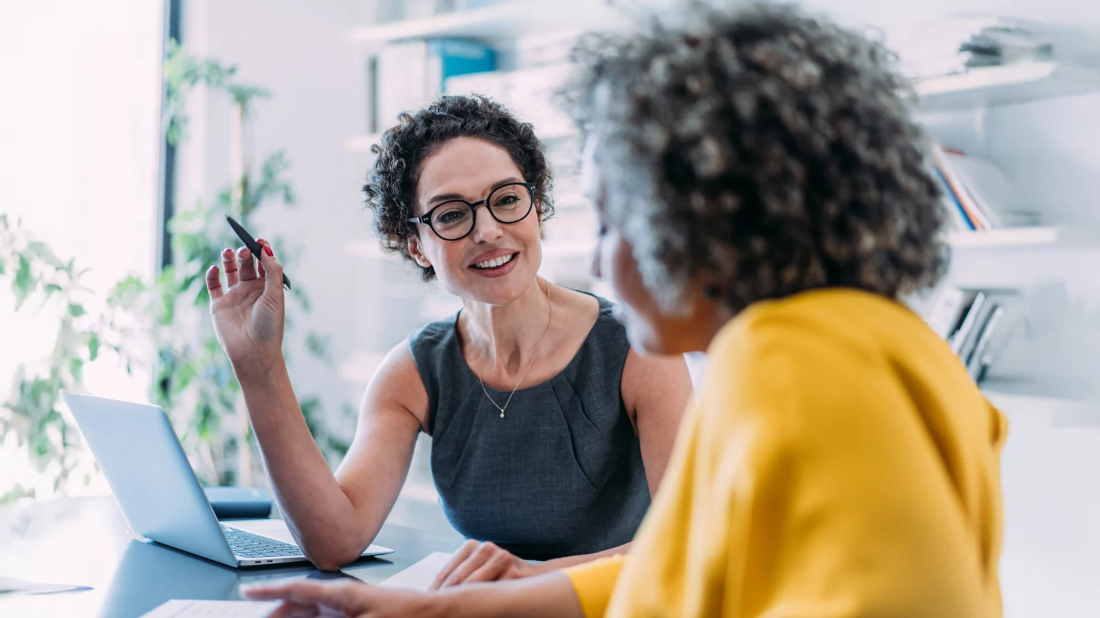 Two female colleagues talking to each other at an office.