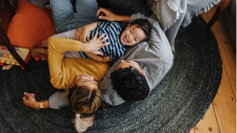 Family laying on the floor playing happily with young son