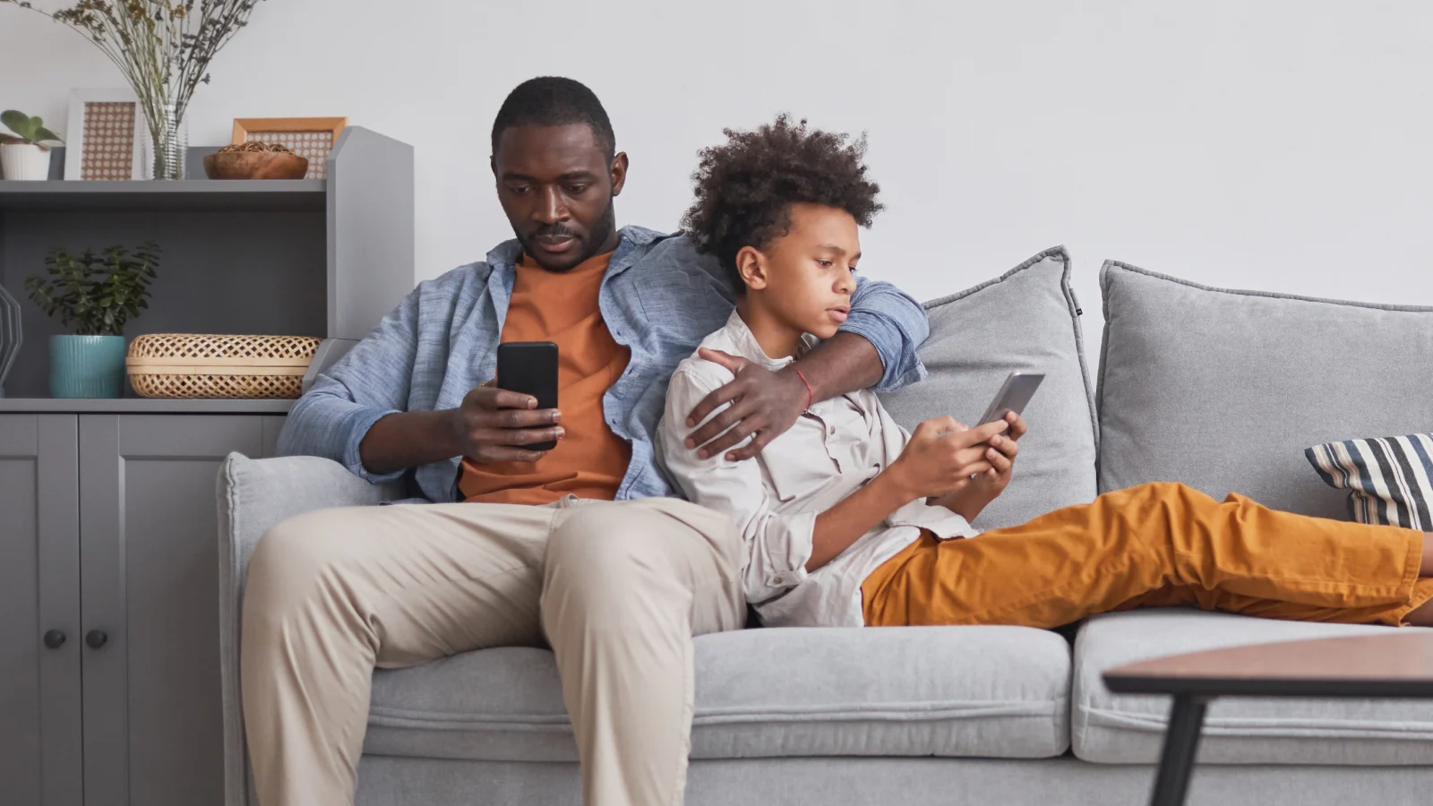 A single view of the whole family's care plans - father and son on couch looking at their own phones